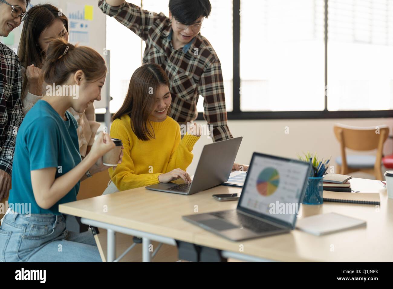 Eine Gruppe junger Unternehmensgründungen feiert einen Triumph mit Rüstung, verschiedene Geschäftsleute freuen sich über den Erfolg in der Vorstandsetage. Stockfoto