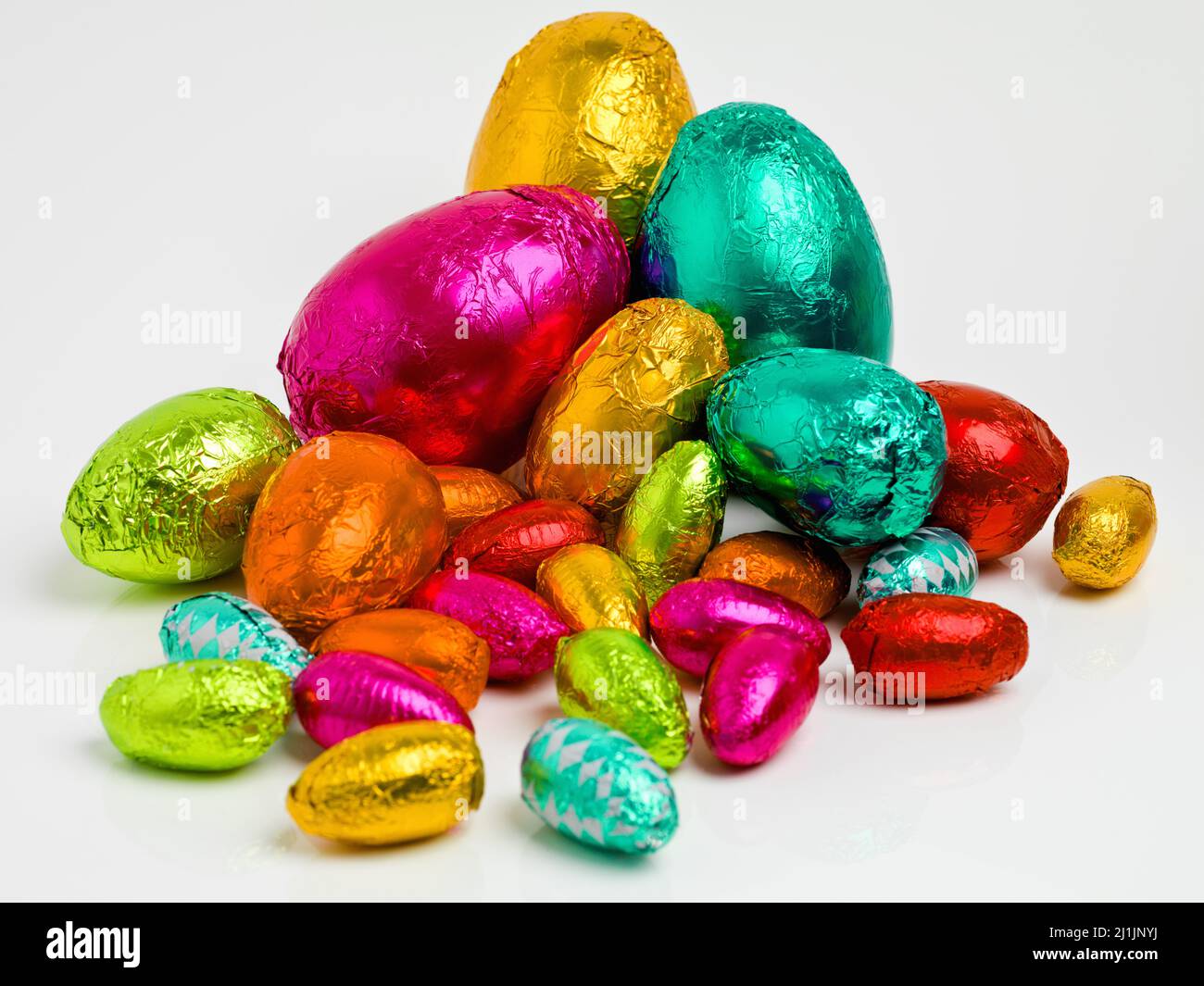 Osteresswaren. Studio-Aufnahme einer schillernden Reihe von bunten ostereiern, die in Folie eingewickelt sind. Stockfoto