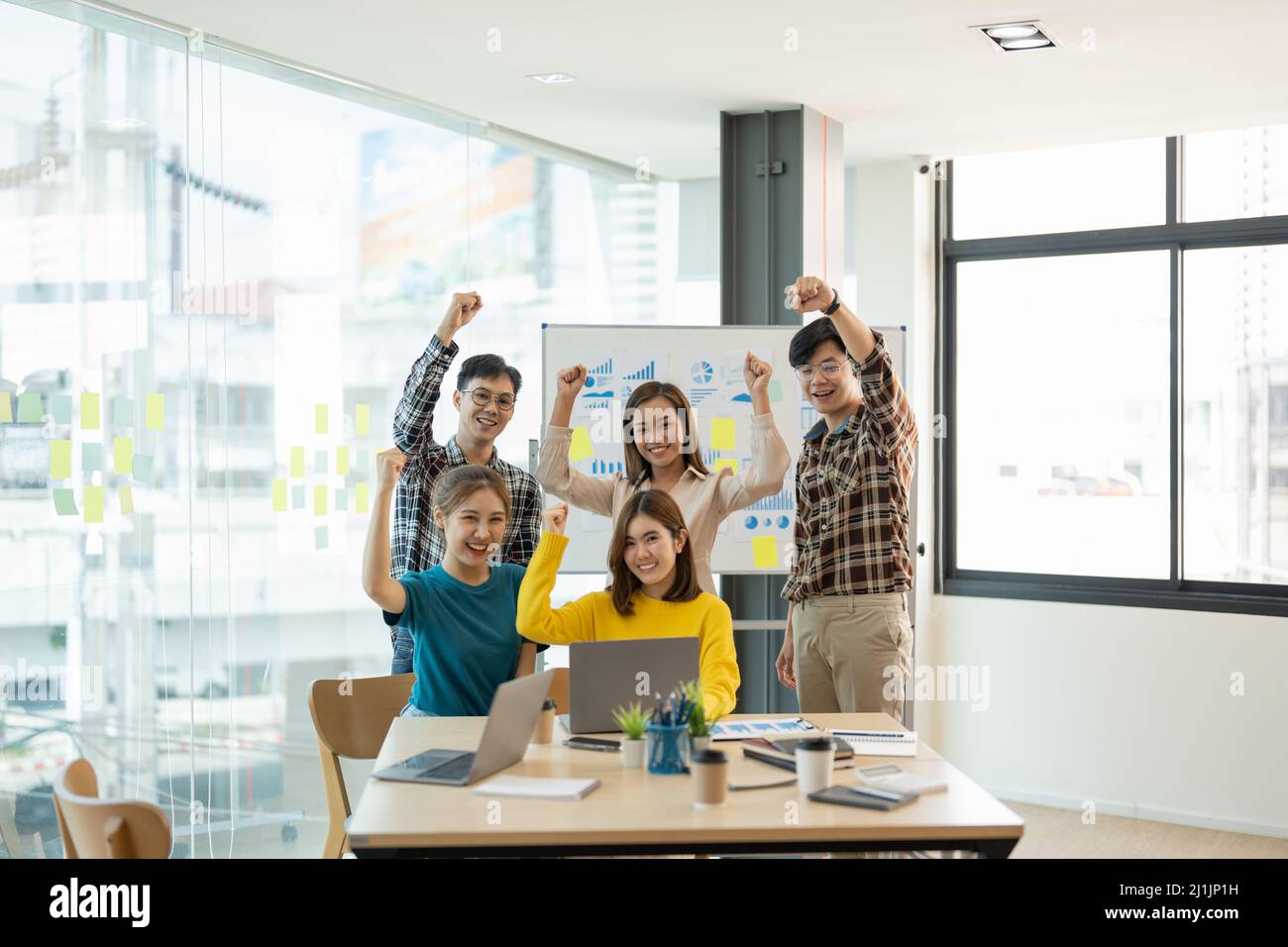 Eine Gruppe junger Unternehmensgründungen feiert einen Triumph mit Rüstung, verschiedene Geschäftsleute freuen sich über den Erfolg in der Vorstandsetage. Stockfoto