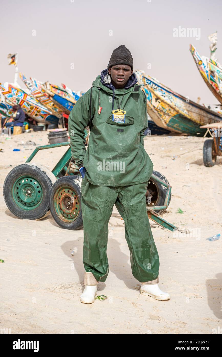 Ein junger schwarzafrikanischer Arbeiter, der auf dem Fischmarkt, Nouakchott, Mauretanien, viel frischen Fisch herunterlädt Stockfoto