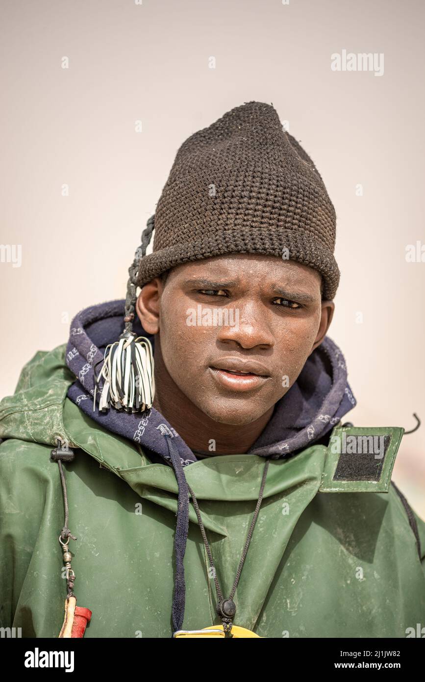 Porträt eines jungen schwarzafrikanischen Arbeiters, der auf dem Fischmarkt in Nouakchott, Mauretanien, viele frische Fische herunterlädt Stockfoto