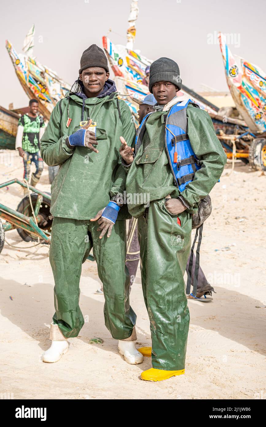 Zwei junge schwarzafrikanische Arbeiter laden auf dem Fischmarkt, Nouakchott, Mauretanien, jede Menge frischen Fisch herunter Stockfoto