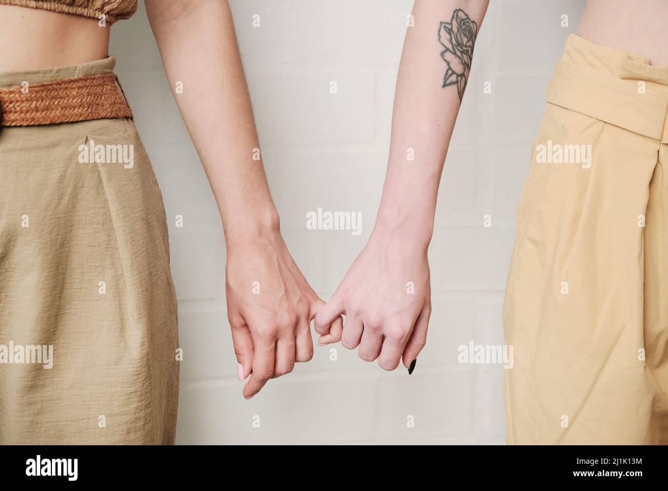 Nahaufnahme von unkenntlichen Lesben, die den Pinkie-Finger an der Wand halten Stockfoto