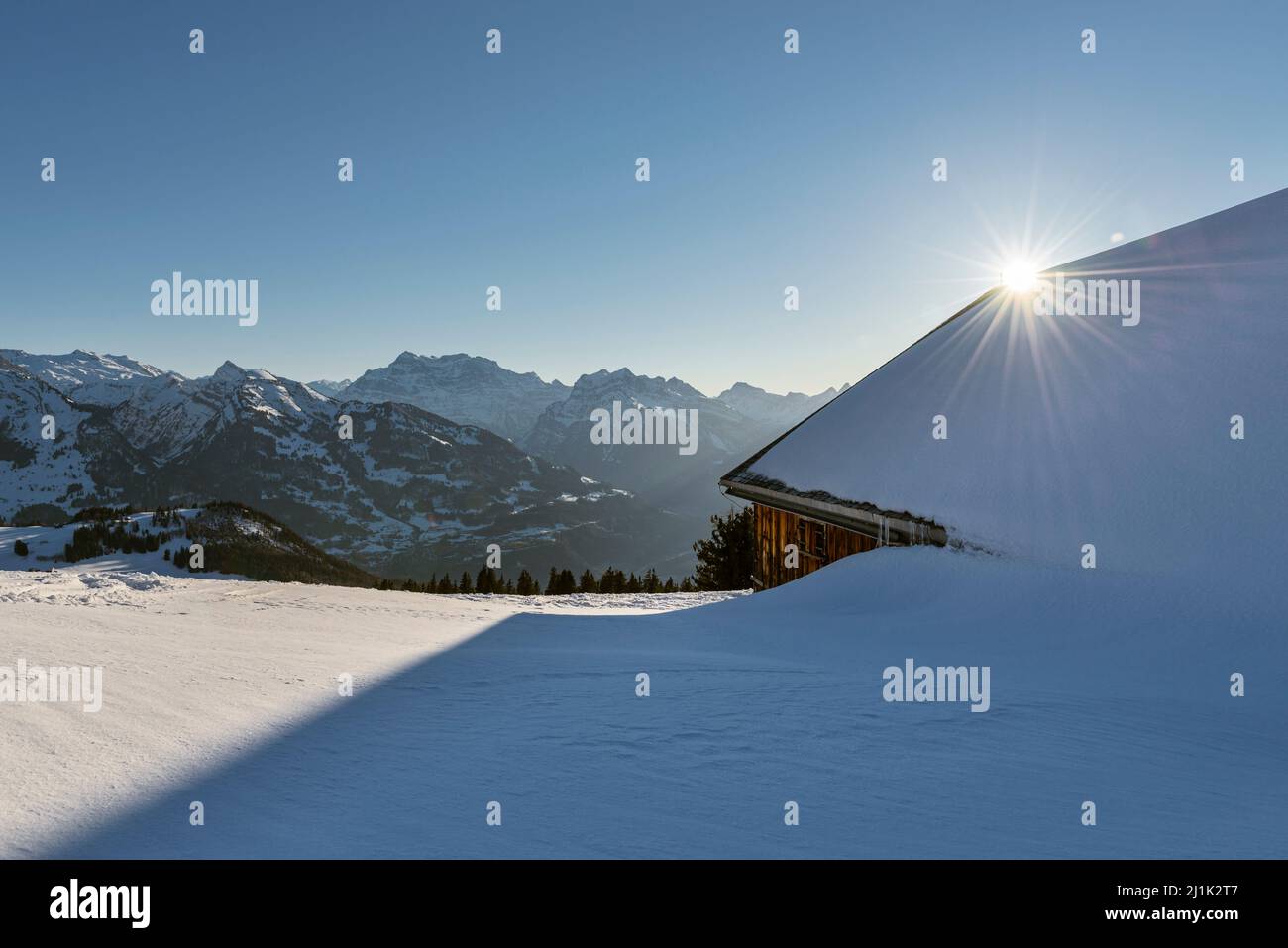 Verschneite Almhütte vor dem Panorama der Glarner Alpen in der Morgensonne, Kanton Sankt Gallen, Schweiz Stockfoto