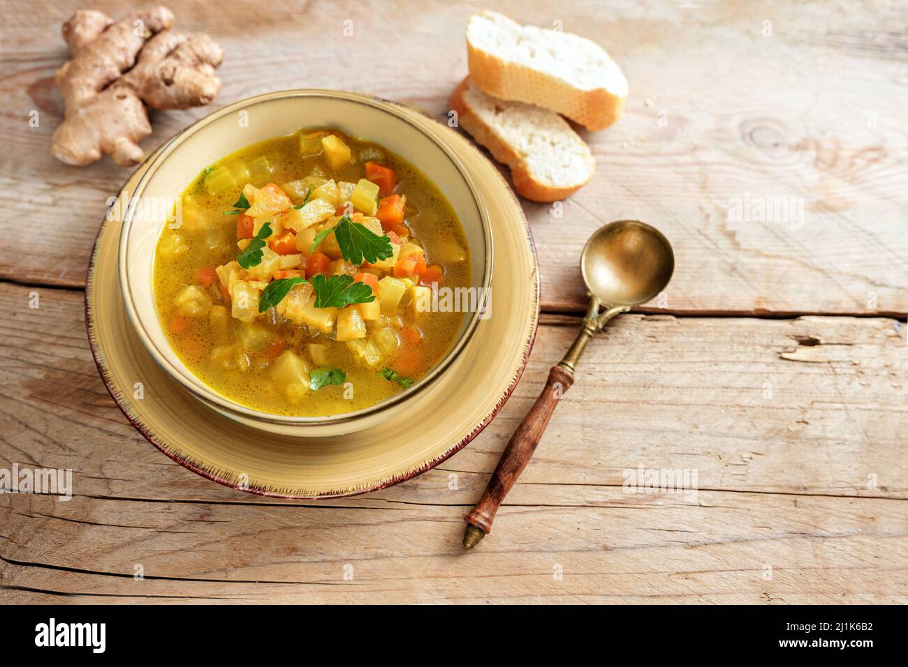 Gemüse-Currysuppe aus Karotte und Sellerie mit Kurkuma, Ingwer und Petersilie in einer Schüssel auf einem rustikalen Holzdielentisch garnieren, Platz kopieren, ausgewählt f Stockfoto