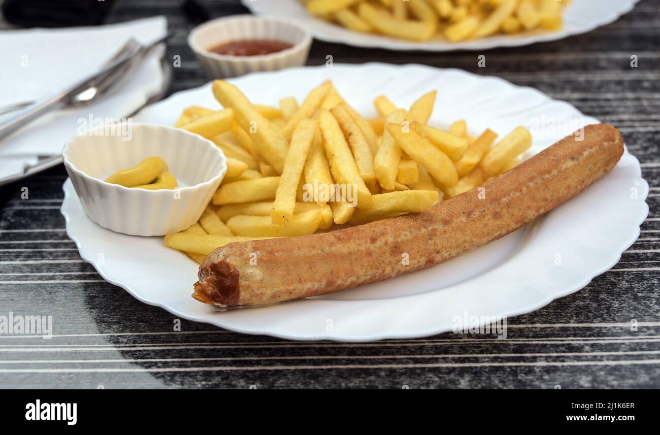 Deutsche Bratwurst oder gegrillte Wurst mit Pommes frites, Senf und Ketchup auf einem Teller in einem Straßenrestaurant, ungesundes Fast Food, ausgewählter Fokus, nar Stockfoto