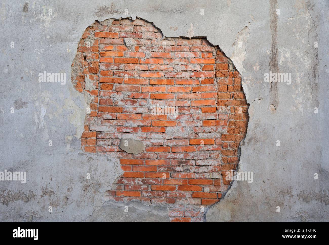 Alte und gealterte Wand mit abblätterndem Gips und Mauerwerk aus orangefarbenem Ziegel. Textur und Struktur der Oberfläche. Gebäudedetails. Zentrale Zusammensetzung Stockfoto
