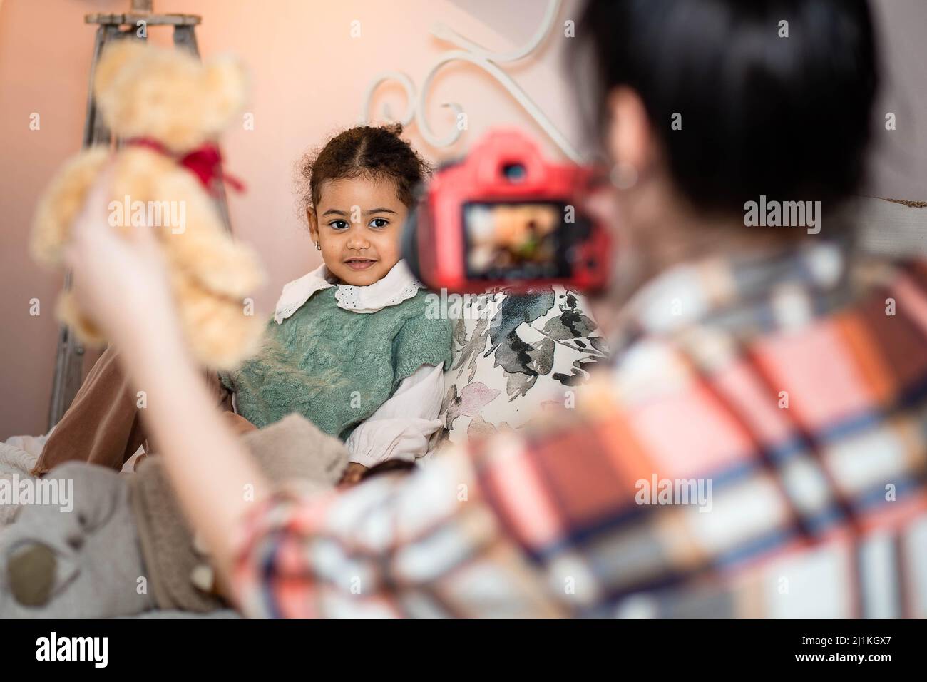 Fotografin fotografiert ein kleines multiethnisches Mädchen in einem Fotoshooting Stockfoto