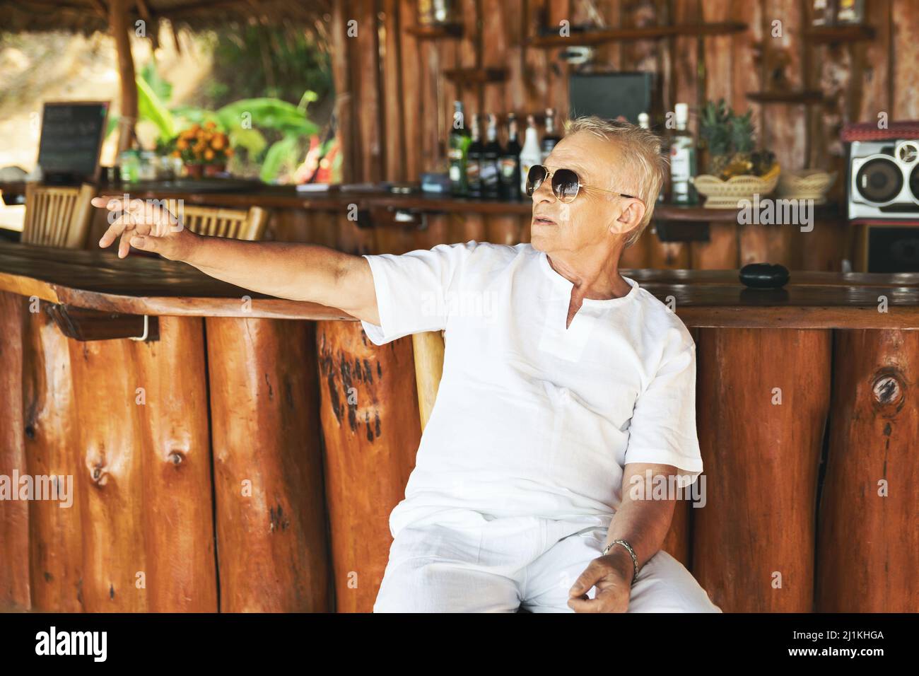 Glücklicher älterer Mann, der in der Strandbar sitzt Stockfoto