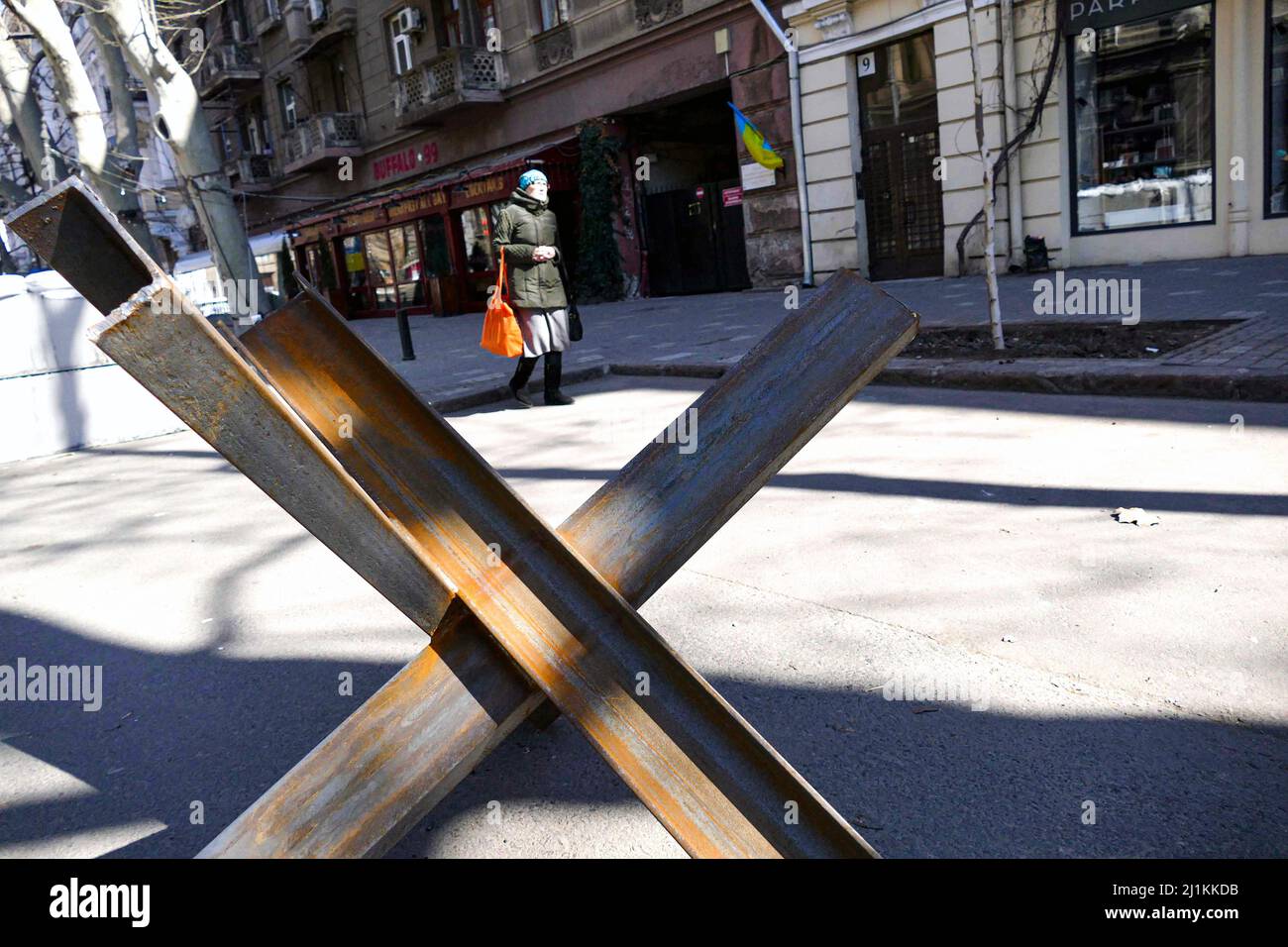 ODESA, UKRAINE - 24. MÄRZ 2022 - Eine Frau geht auf einer Straße, die von einem Panzerabwehrhindernis, dem tschechischen Igel, blockiert ist, wie die Ukraine schon Abb. Stockfoto