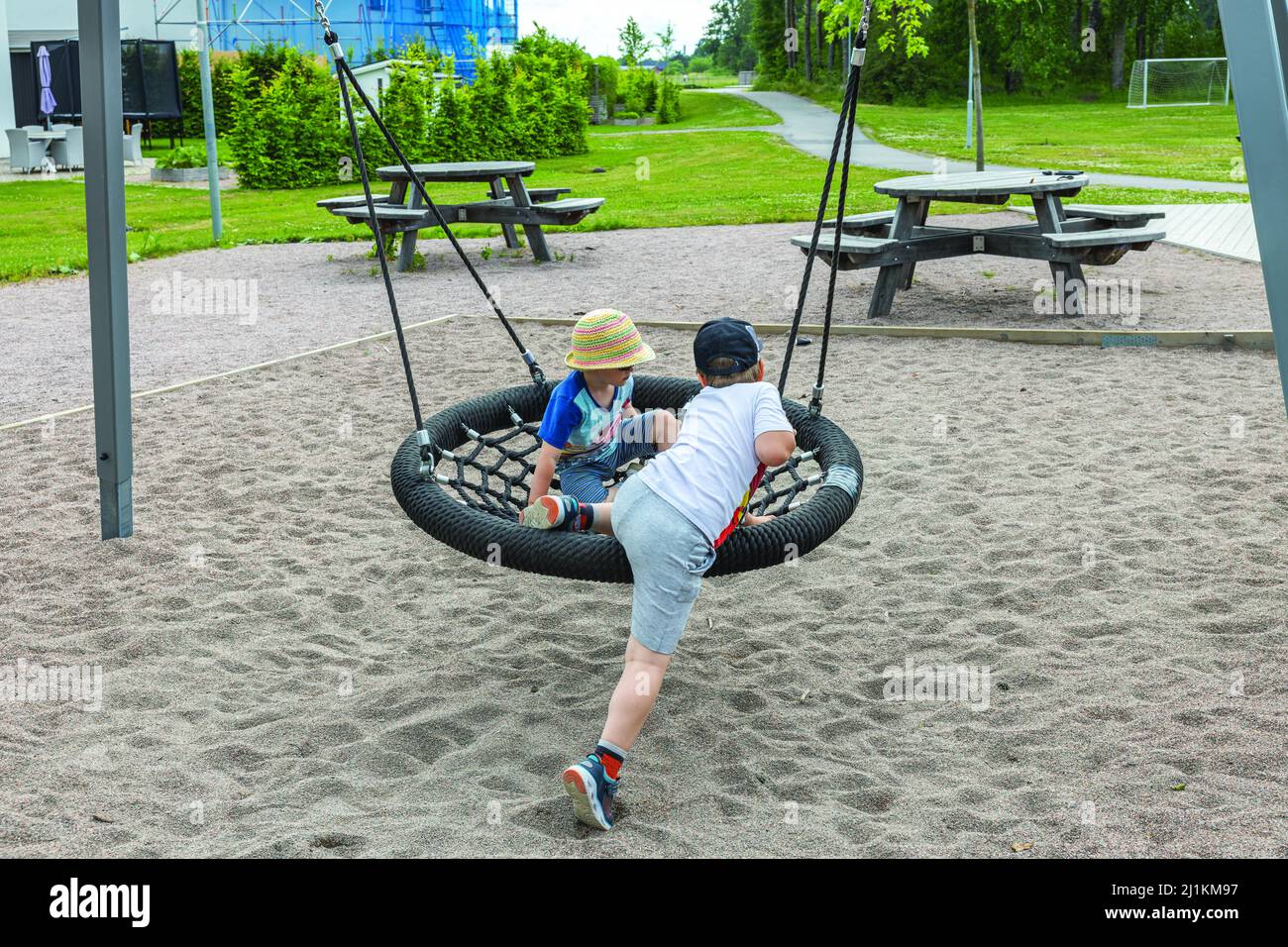 Wunderschöne Aussicht auf Kinder, die an sonnigen Sommertagen auf Schaukel im Freien schaukeln. Schweden. Stockfoto