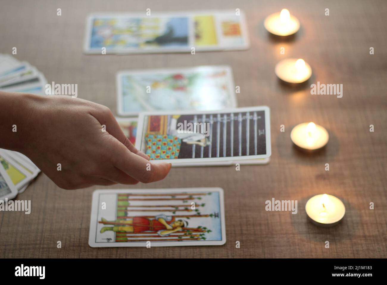 Istanbul, Türkei, 06 2022. März: Wahrsagerin, zeigt oder hält ausgerichtete Tarot-Karten, die mit der Hand auf einem braunen Holztisch gelesen werden, brennende Teekerzen. Stockfoto