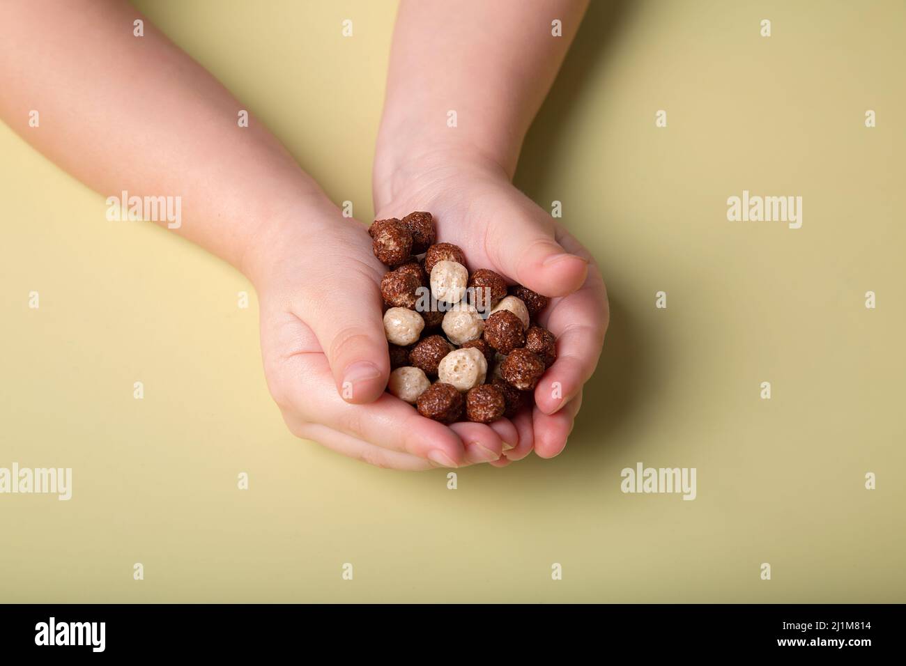 Die Hände der Kinder halten Schokolade und weiße Maiskugeln Stockfoto