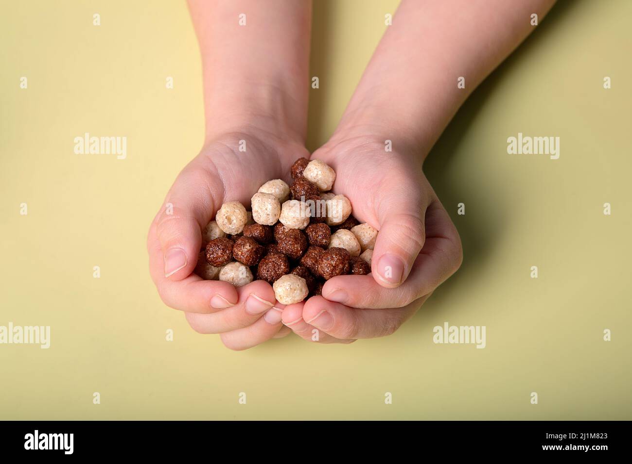 Die Hände der Kinder halten Schokolade und weiße Maiskugeln Stockfoto