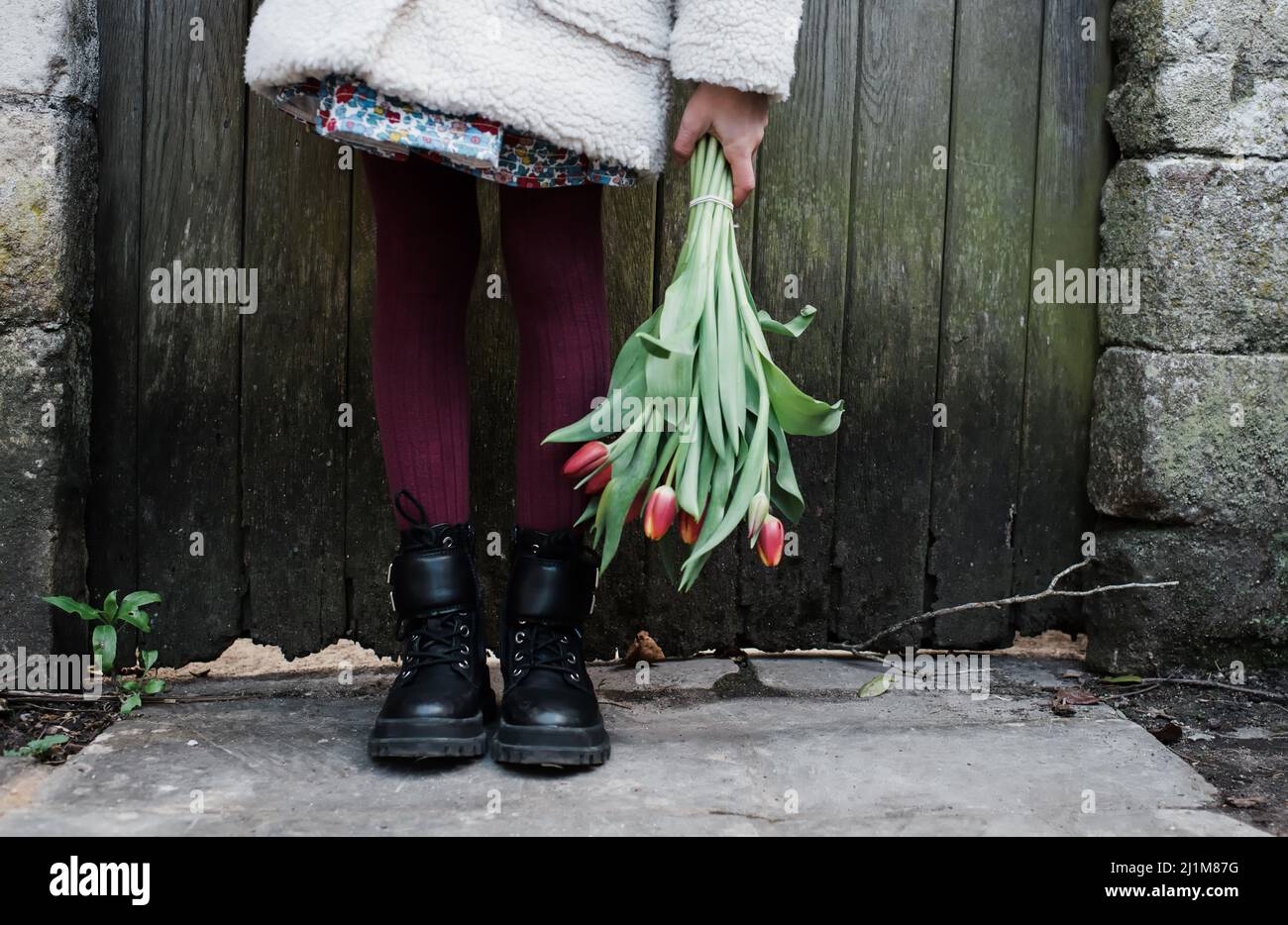 Kinderfüße und Hand halten Blumen in England Stockfoto