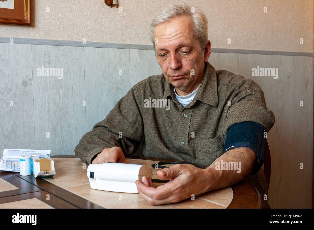 Ein Mann von 55-60 Jahren sitzt in seinem Haus, am Tisch, und ich Stockfoto