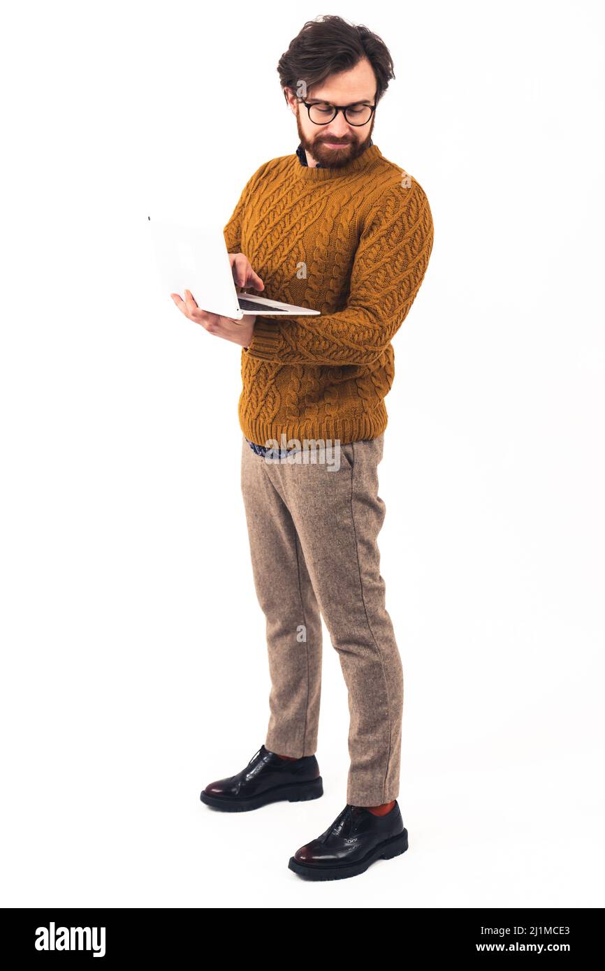 Full-shot junge gut aussehende kaukasischen Mann in Brille und Bart stehen, mit weißen Laptop suchen Hipster Remote Job Online-Bildung Konzept Freizeitkleidung weißen Hintergrund isoliert Studio Schuss . Hochwertige Fotos Stockfoto