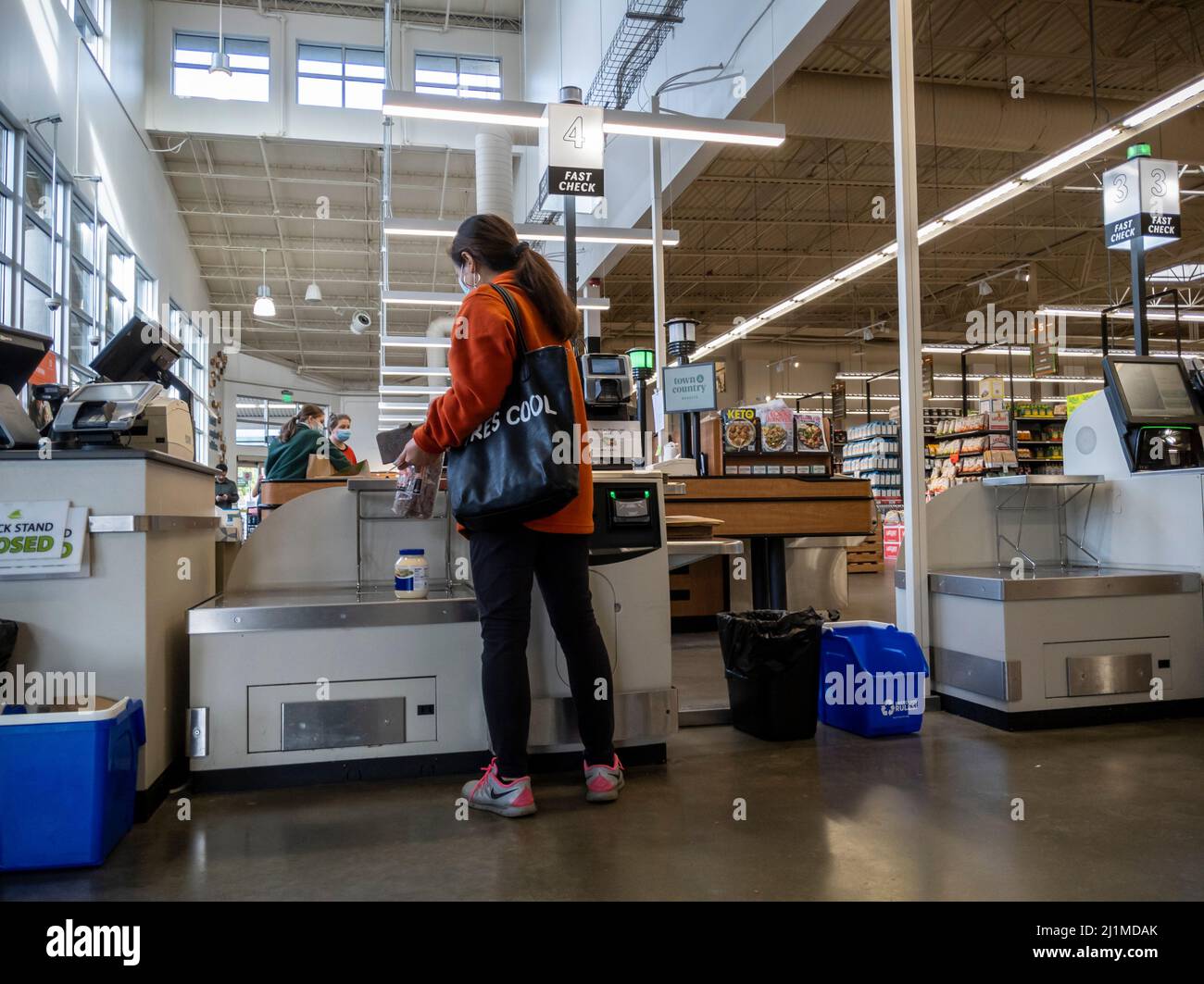 Lynnwood, WA USA - ca. März 2022: Blick auf eine Frau in einem roten Mantel, die im Self-Checkout-Bereich eines Stadt- und Landmarktes auscheckt Stockfoto
