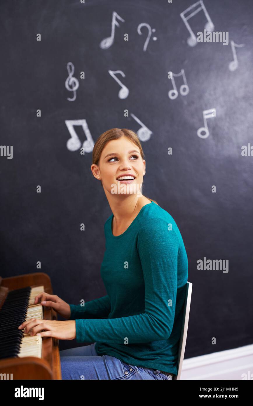 Musik machen. Aufnahme einer Frau, die vor dem Hintergrund von Musiknoten Klavier spielt. Stockfoto