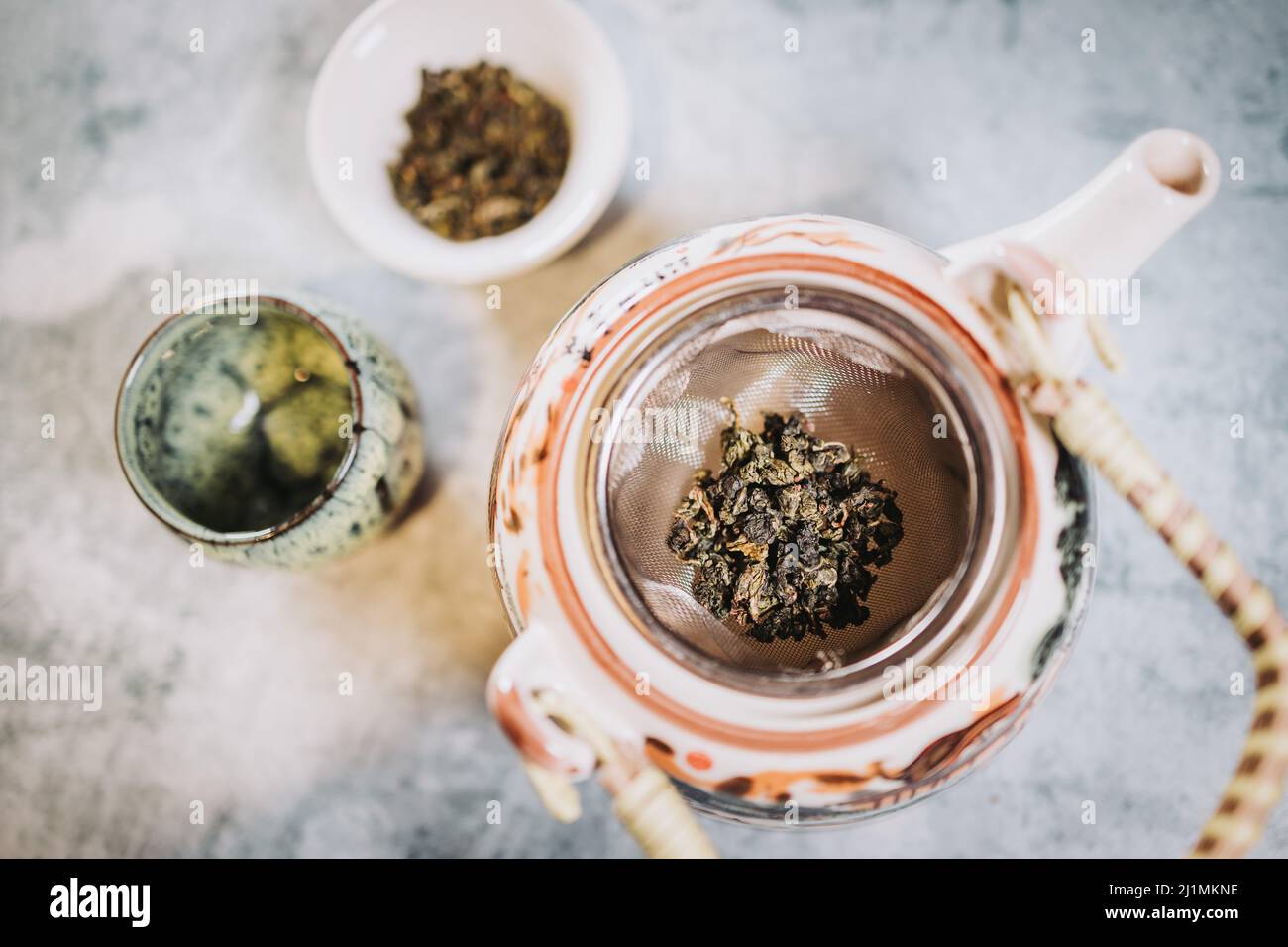 Teezeit. Teekannen, eine Tasse und getrockneter Tee stehen bereit, um serviert zu werden, vor einem grauen Hintergrund. Infusion. Stockfoto