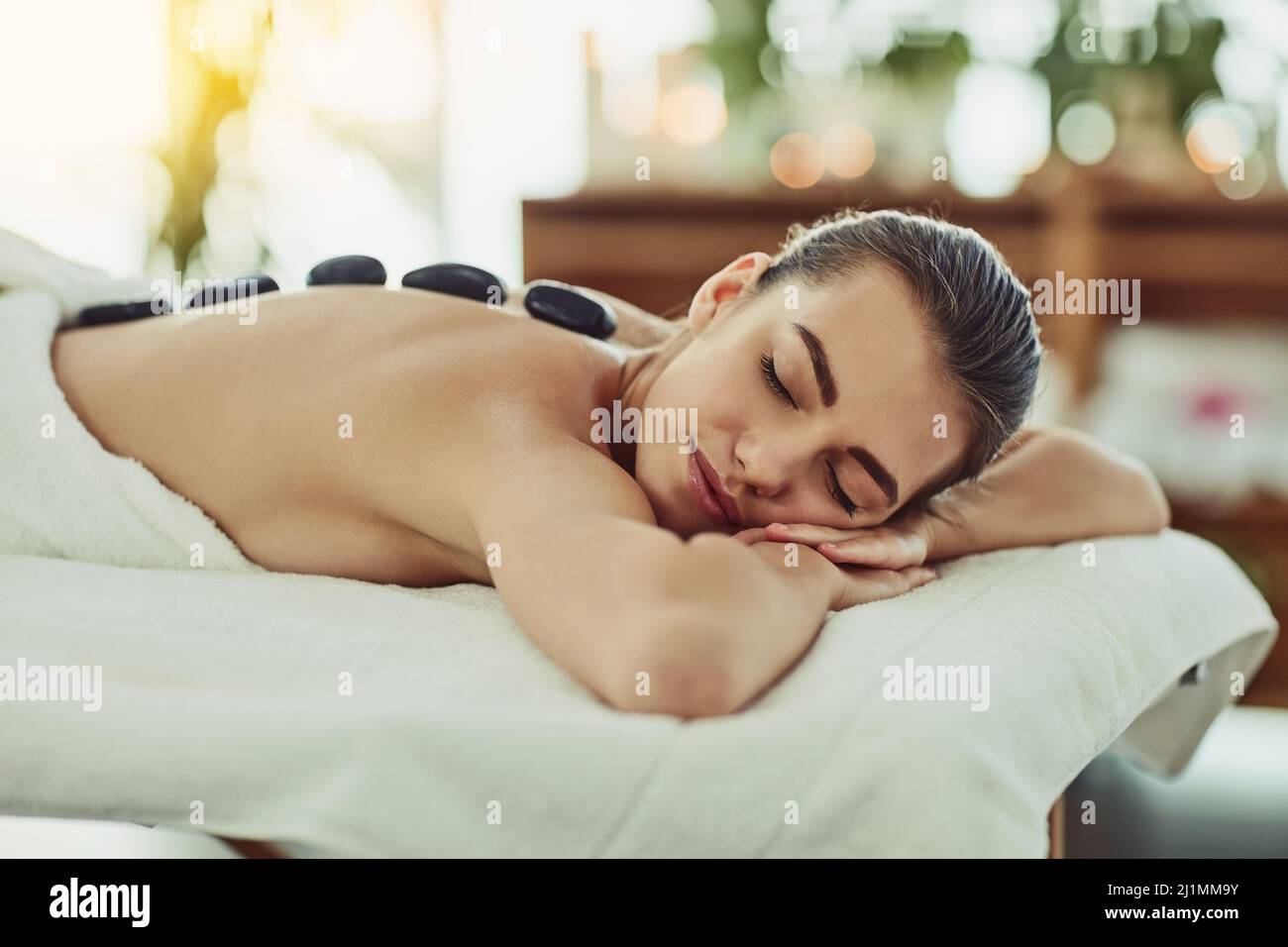Mit Hitze direkt auf die Muskeln zu bringen. Aufnahme einer attraktiven jungen Frau, die in einem Beauty Spa eine Hot Stone Massage bekommt. Stockfoto