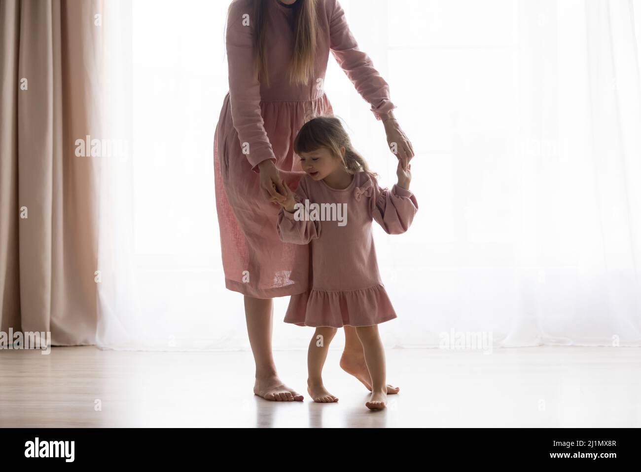 Fürsorgliche junge Mutter hilft Kind zu Hause zu Fuß. Stockfoto