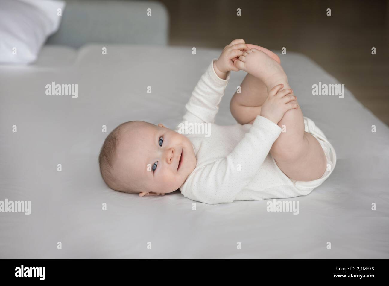 Porträt eines glücklichen Neugeborenen, das auf dem Bett liegt. Stockfoto