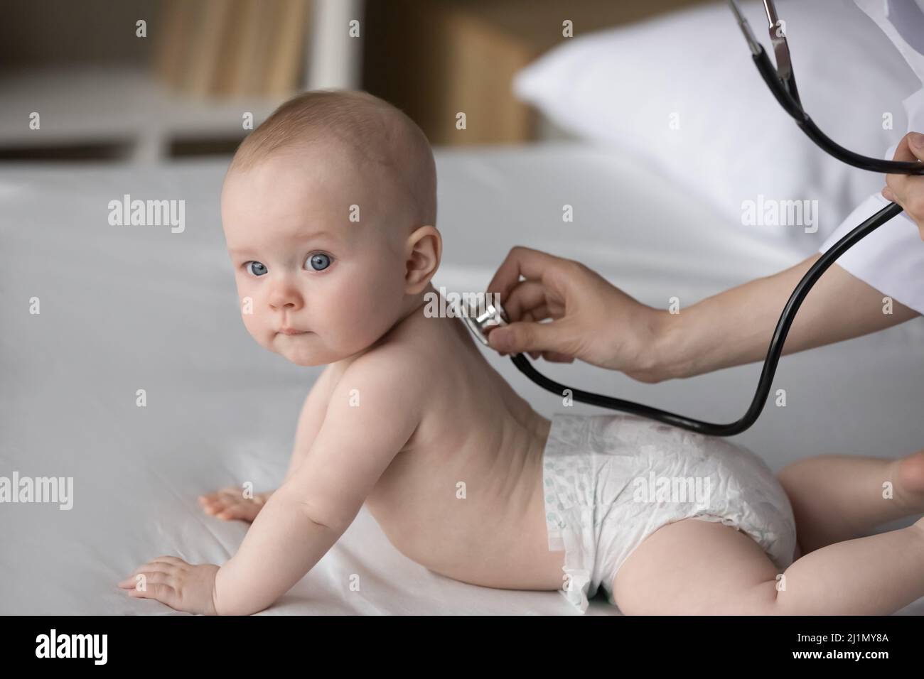 Fürsorglicher medizinischer Arbeiter, der die Untersuchung von kleinen paar Monaten Kind macht. Stockfoto