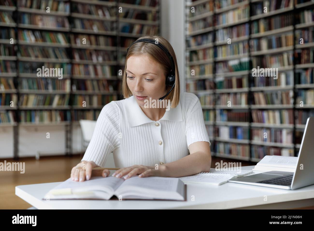 Student Mädchen sitzen am Tisch lesen Lehrbuch Studium in der Bibliothek Stockfoto