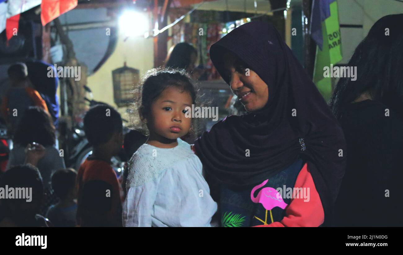 Jakarta, Indonesien - 01 02 2021: Eine Frau in einem Hijab hält ein Mädchen mit einem glücklichen Blick, während sie die Feier der indonesischen Unabhängigkeit von 72. beobachtet Stockfoto