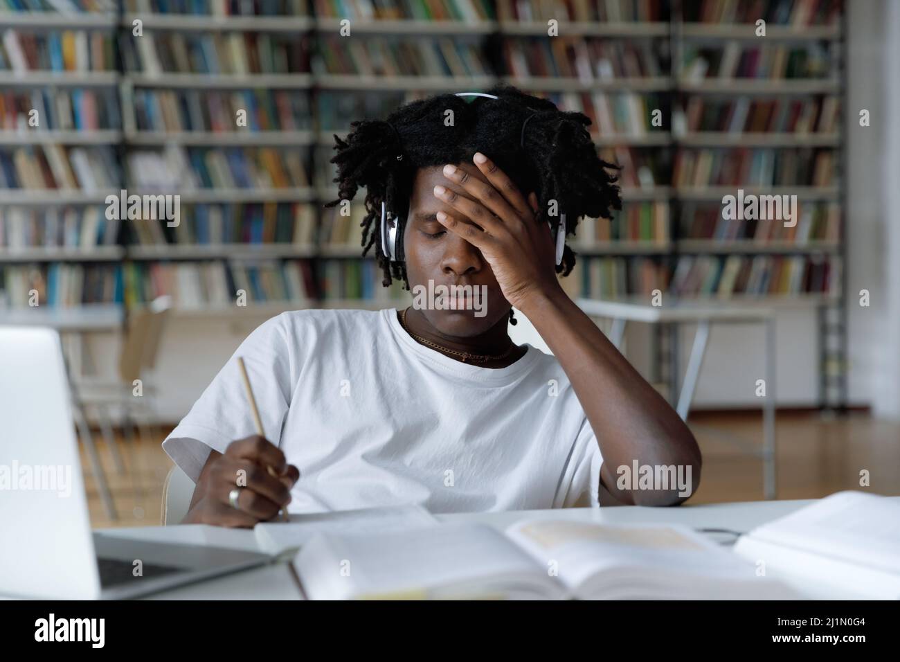 Afrikanischer Student fühlt sich müde aufgrund langer Vorbereitungen für College-Prüfung Stockfoto