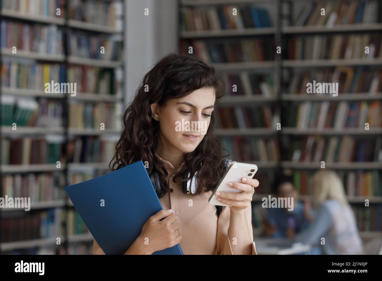 Student Mädchen mit Smartphone in der Bibliothek stehen Stockfoto