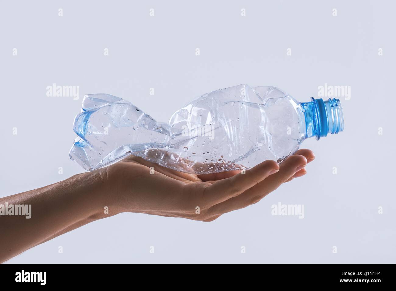 Weibliche Hand mit einer gebrauchten Plastikflasche Stockfoto