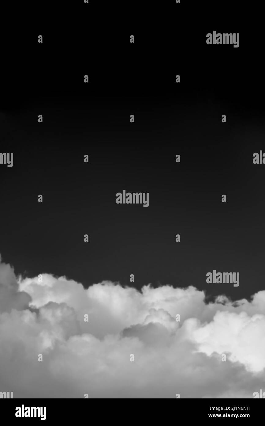 Flauschige Wolken am klaren schwarzen Himmel mit Kopierraum monochrom Stockfoto