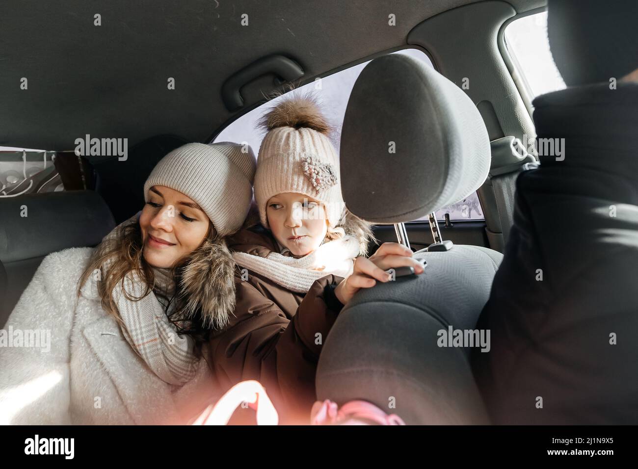 Mutter und Tochter im Auto in warmen Kleidern fahren in den Urlaub Stockfoto