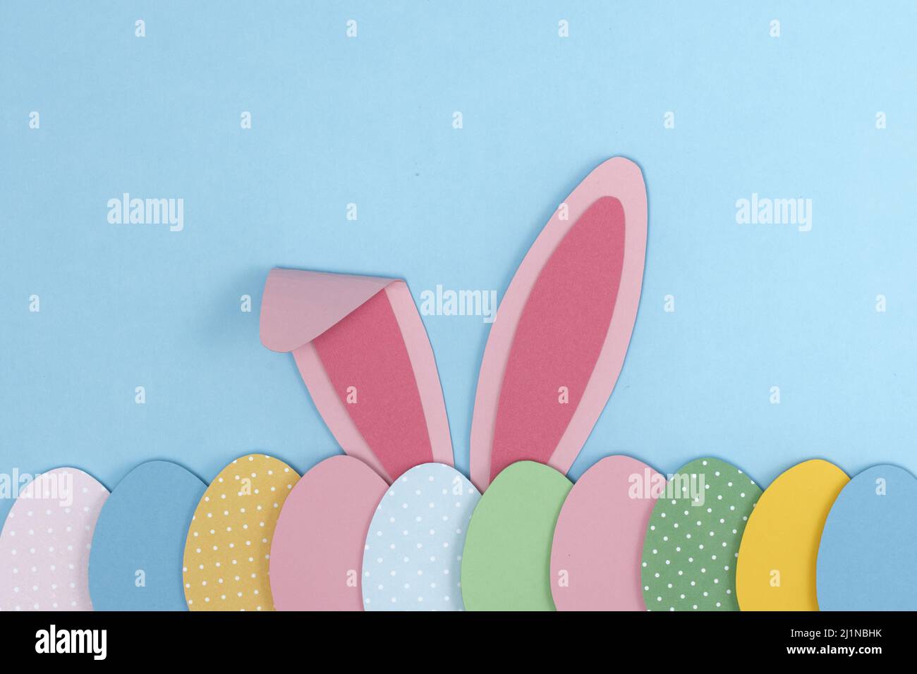 Hasenohren in Pink Bunny und bemalte Ostereier, die Papier auf blauem Hintergrund ausschneiden. Vorlage für Ostern-Grußkarten. Kreative ostern Minimal Konzept wi Stockfoto