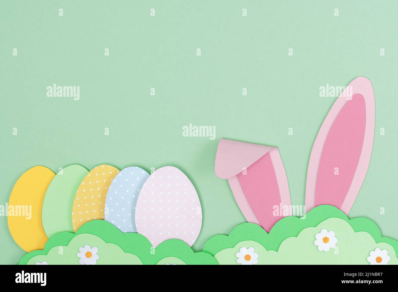 Hasenohren in Pink Bunny und bemalte Ostereier aus Papier. Frohe Ostern Hintergrund mit Hase verstecken im Gras. Vorlage für Ostern-Grußkarten. Creativ Stockfoto