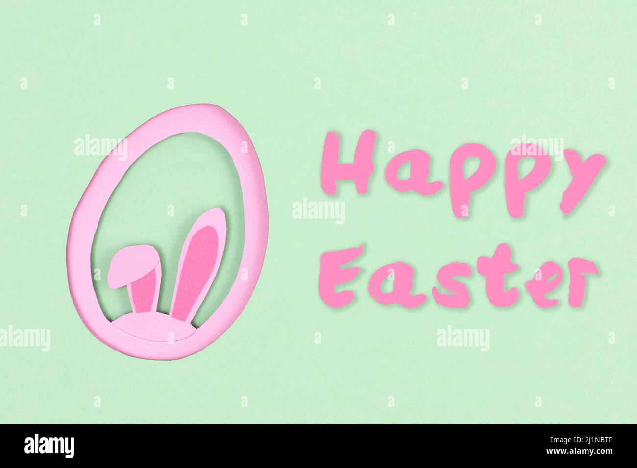 Papierschnitt aus rosa osterhasen-Ohren und grüner Eierform mit der Aufschrift Frohe Ostern. Eine Osterkarte mit einer Kopie des Ortes für den Text. Crea Stockfoto