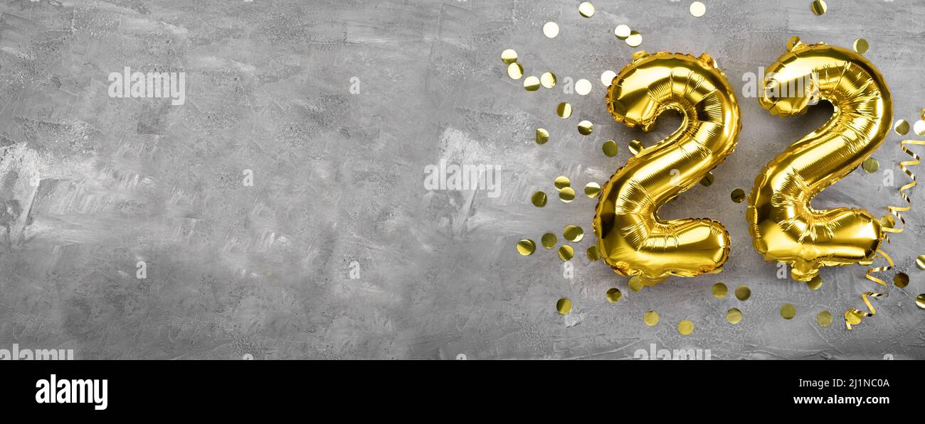 Gelbe Folienballon-Nummer, Nummer zweiundzwanzig auf einem betonierten Hintergrund. Geburtstagskarte mit Aufschrift 22. Jubiläumskonzept. Zum Jubiläum Stockfoto