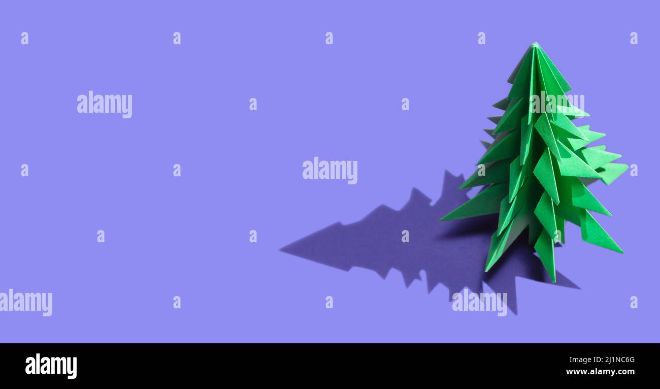 Origami grüner Weihnachtsbaum vor dem Hintergrund der trendigen 2022 Farbe des Jahres sehr Peri. Kreativer Hintergrund für die Urlaubssaison. Farbe des Th Stockfoto