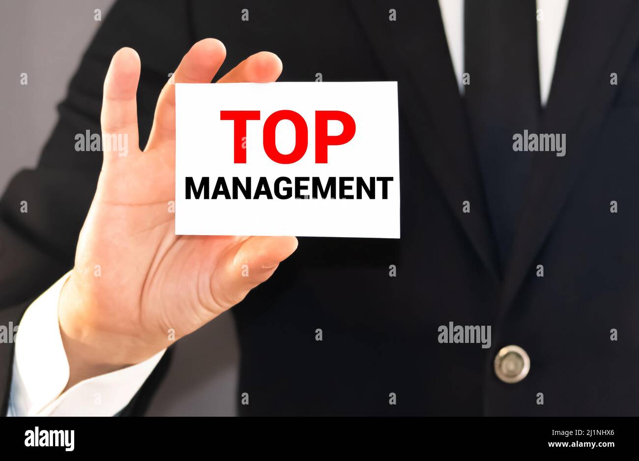 Geschäftsmann zeigt eine Karte mit dem Wort Top Management. CEO Position Geschäftskonzept. Stockfoto
