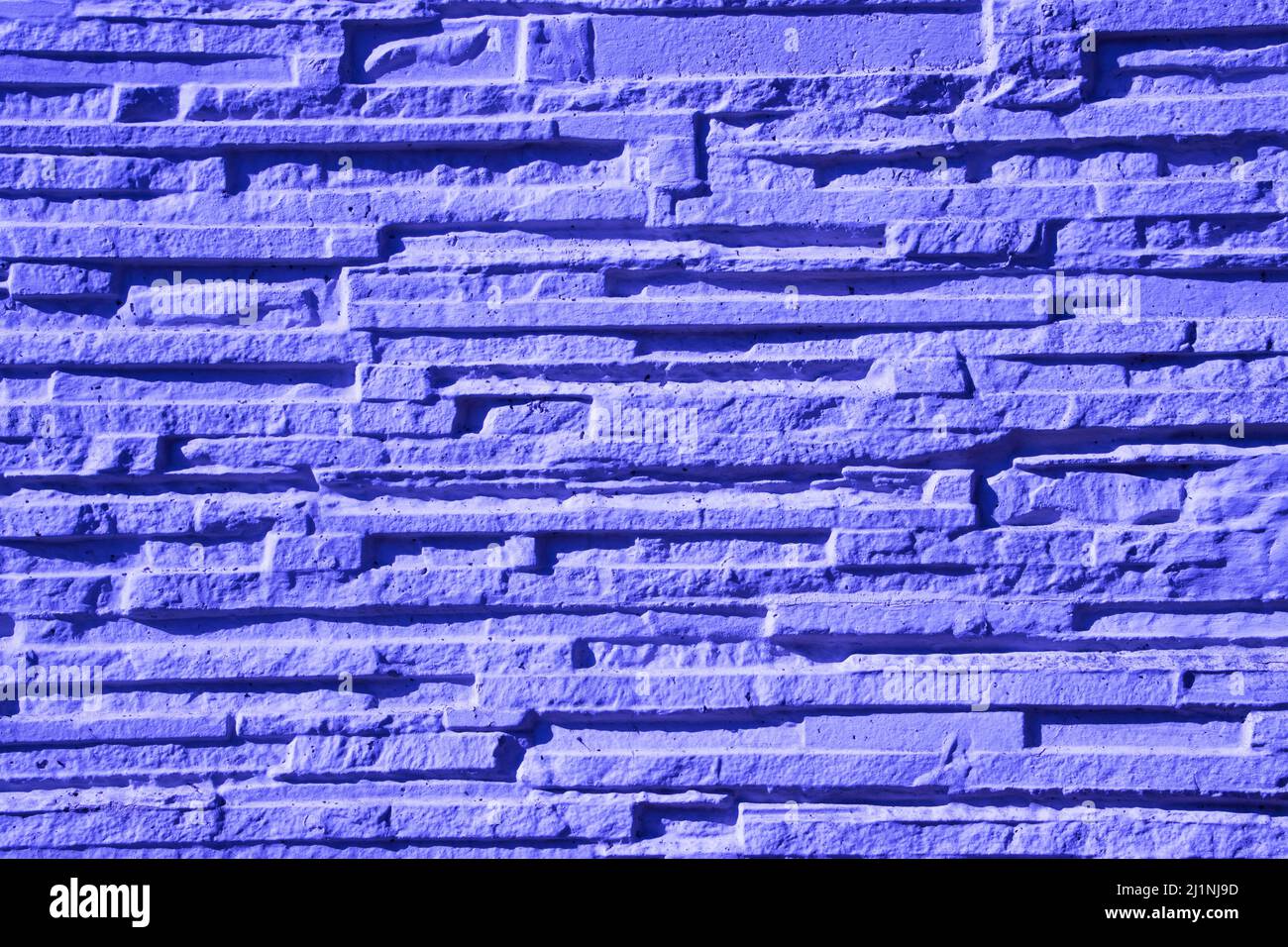 Hellviolett schmale Steinwand Hintergrund Textur in violett oder sehr peri gefärbt Stockfoto