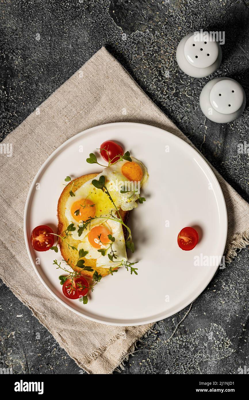 Spiegeleier auf Toast, Kirschtomaten und Rucola Microgreens. Leckeres und gesundes Frühstücksrezept. Draufsicht. Speicherplatz kopieren Stockfoto