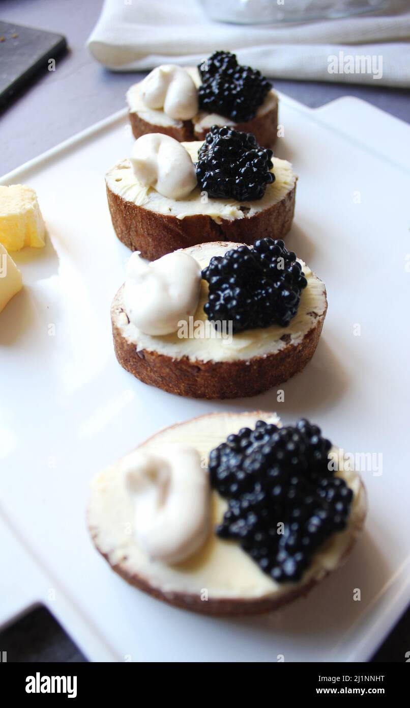 Schwarze Kaviar-Bruschetta auf weißem Teller Stockfoto