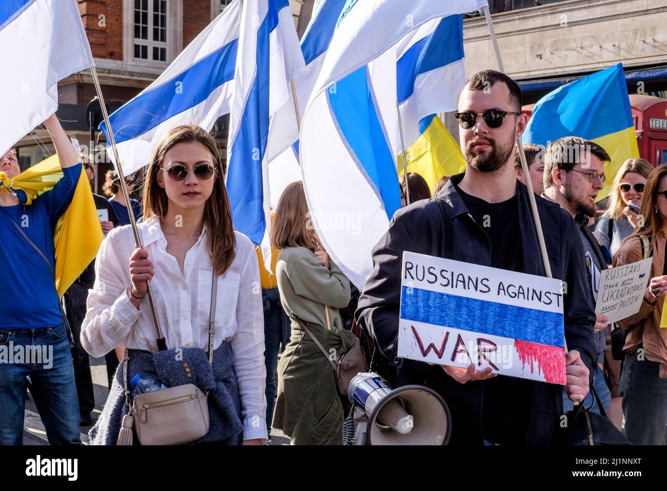London, 26.. März 2022. Tausende von Menschen treten mit der Ukraine zusammen, marschieren und mahnten im Zentrum von London, um gegen die russische Invasion zu protestieren. Mitglieder der Bewegung gegen den Krieg schließen sich dem marsch an. Die Bewegung hat eine weiße und blaue Flagge als Symbol ihres Protests angenommen, die den roten Streifen der russischen Flagge ersetzt, um die Verbindung mit Blut und Gewalt sowie militärischer Macht und Autoritarismus zu beseitigen. Sie verweist auch auf die historische Flagge von Veliky Nowgorod, wo die Regierung der Republik Nowgorod den Ruf hatte, demokratische Regierungsführung zu entwickeln. Stockfoto