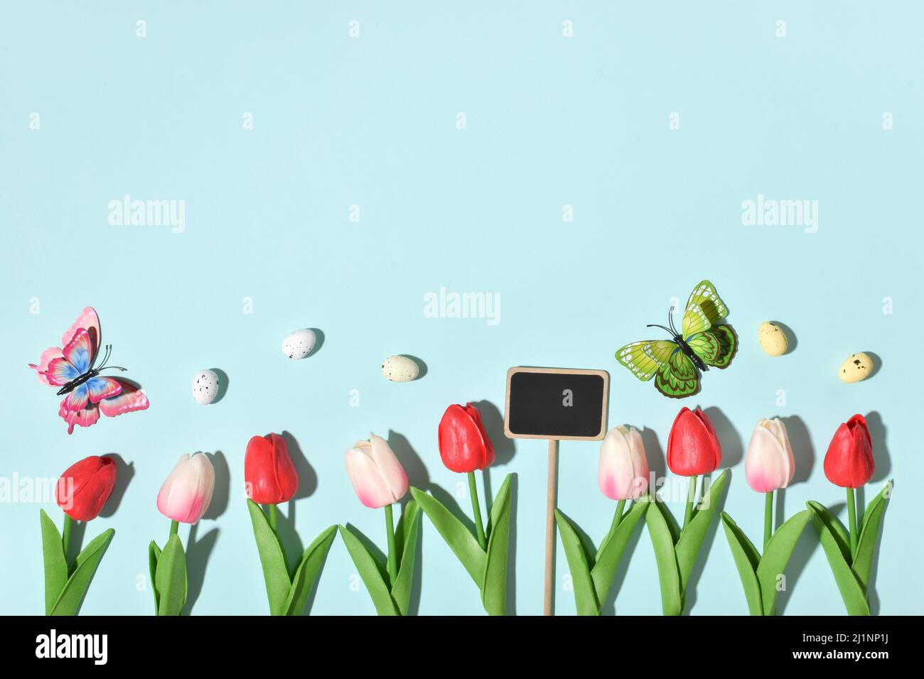 Hintergrund mit Kaninchenohren, Ostereiern und Tulpenblüten. Stockfoto