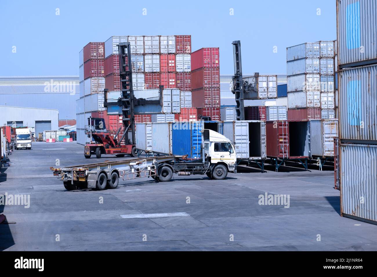 LKW und Containerstapler im Containerlager im Import- und Exportbereich des Hafens Stockfoto