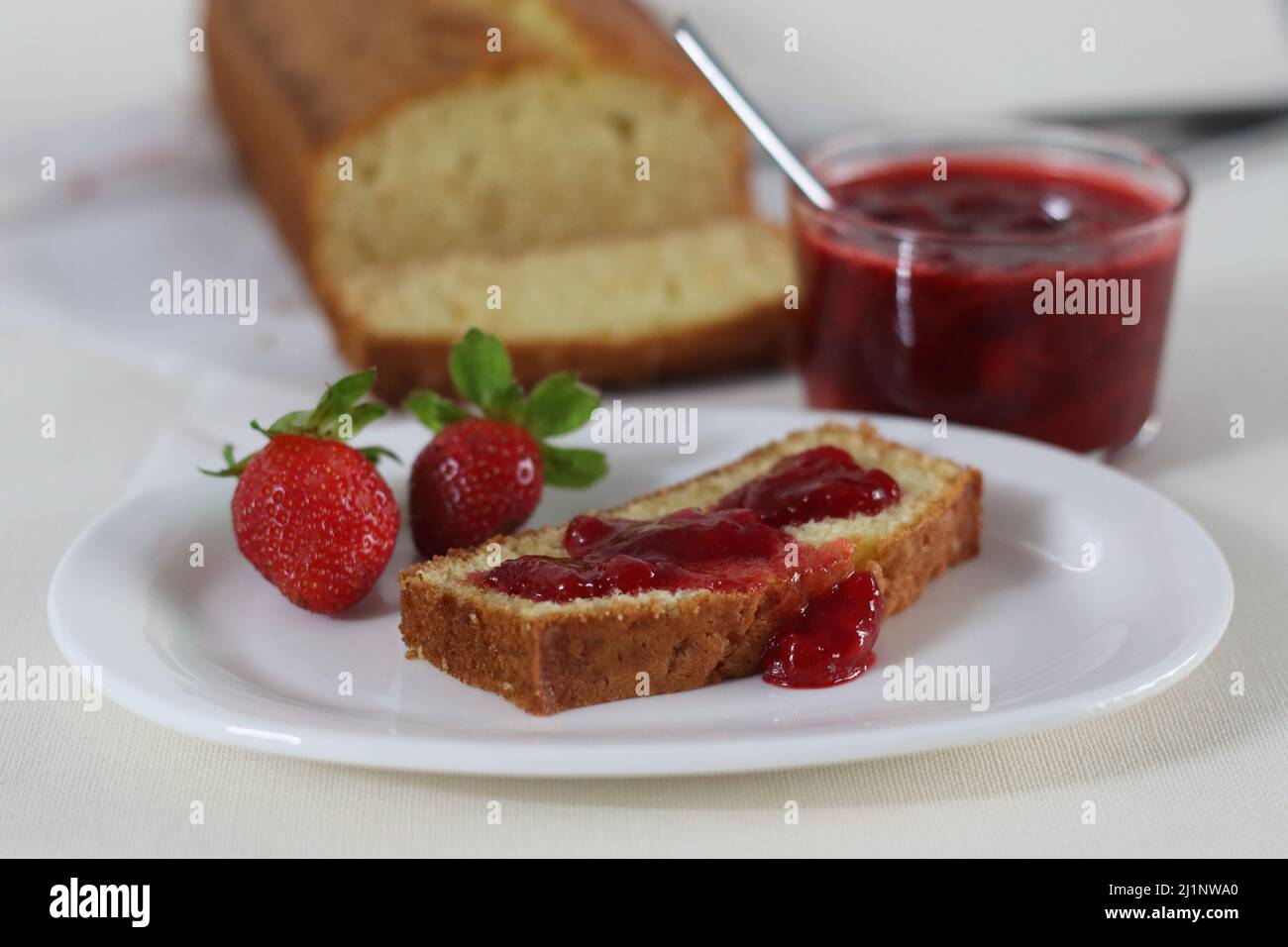 Saure Creme Pfund Kuchen zusammen mit einer Scheibe Pfund Kuchen mit Erdbeersoße Aufstrich. Aufgenommen auf weißem Hintergrund Stockfoto