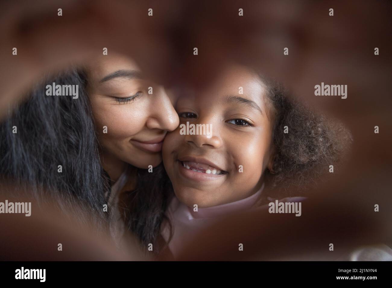 Fröhliche Mutter und Kind mit Zahnlücke macht Hand Herz Stockfoto