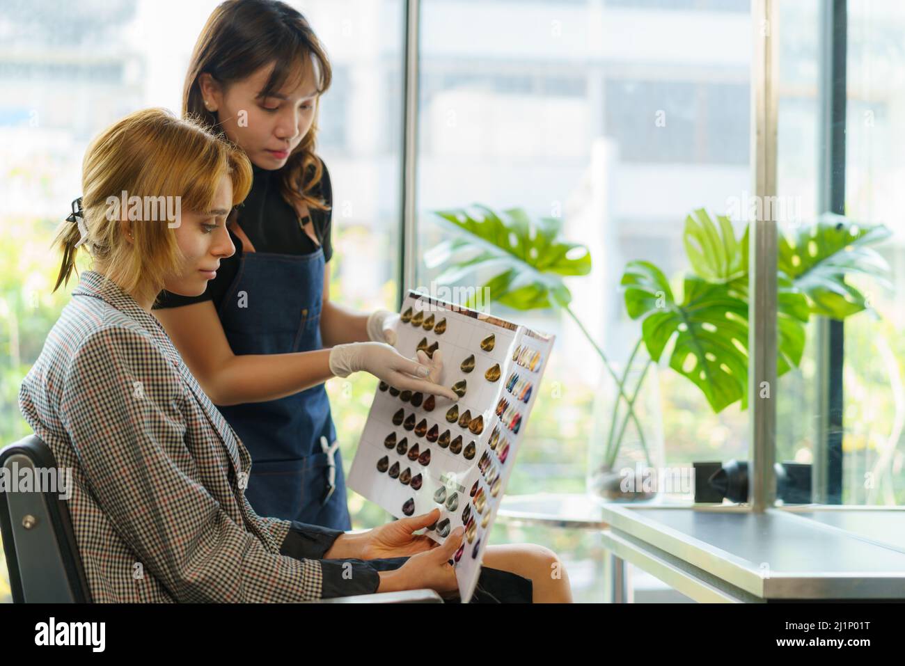 Asiatische Frau Friseurin zeigt Haare Farbtabelle zu ihrem Kunden Diskussion und empfehlen Stockfoto